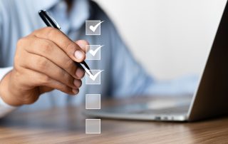 checklist of 5 items with office worker holding a pen and working on laptop