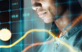 A person looking at a screen with digital financial graphs and data overlays, suggesting analysis or monitoring of stock market trends with advanced Business Intelligence for CFOs.
